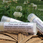Lip balm tubes with white labels, clear plastic, and natural background of flowers and woven basket