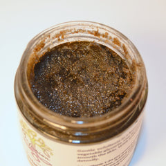 Body scrub in open glass jar with brown granular texture and light brown rim detail
