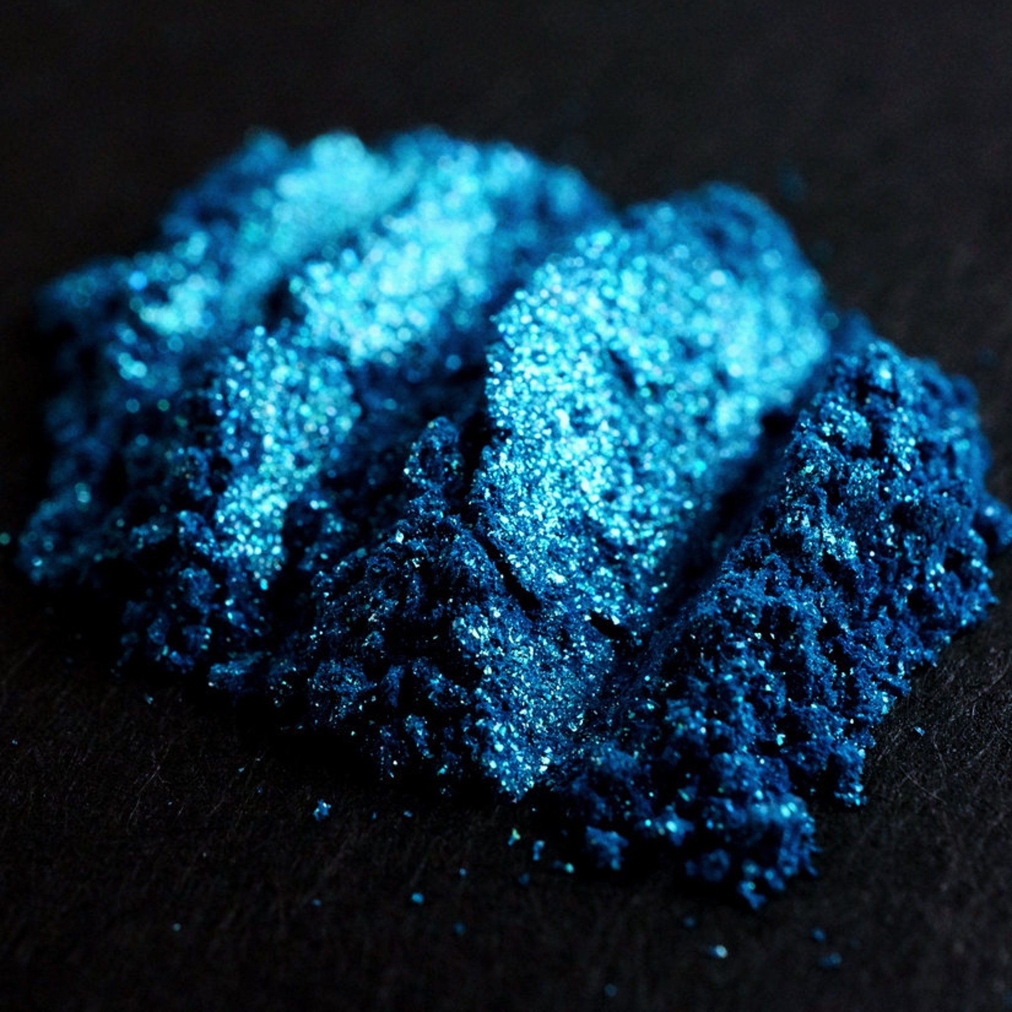 Side view of teal shimmer loose mineral eyeshadow with turquoise and green glitter particles in a sifter jar