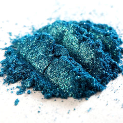 Close-up of teal shimmer loose mineral eyeshadow with turquoise and green glitter particles sparkling in light