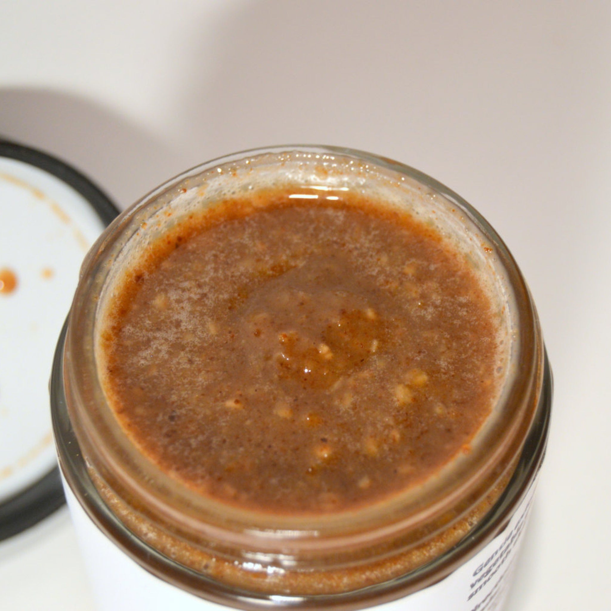 Brown spread in a clear glass jar, with visible texture and white label, open lid visible