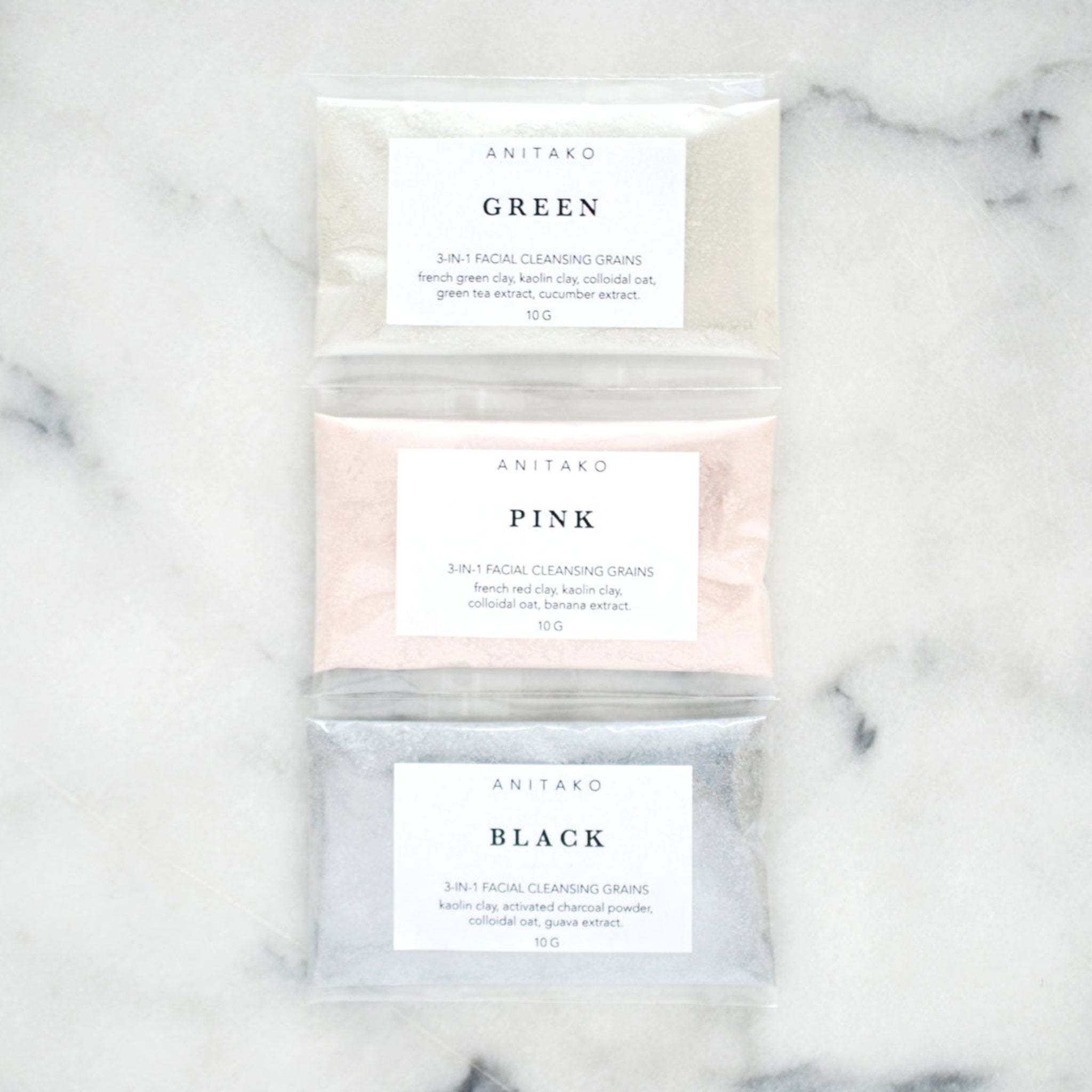 Facial cleansing grains in clear plastic pouches, with ANITAKO labels, in green, pink, and black colors