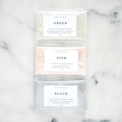 Facial cleansing grains in clear plastic pouches, with ANITAKO labels, in green, pink, and black colors