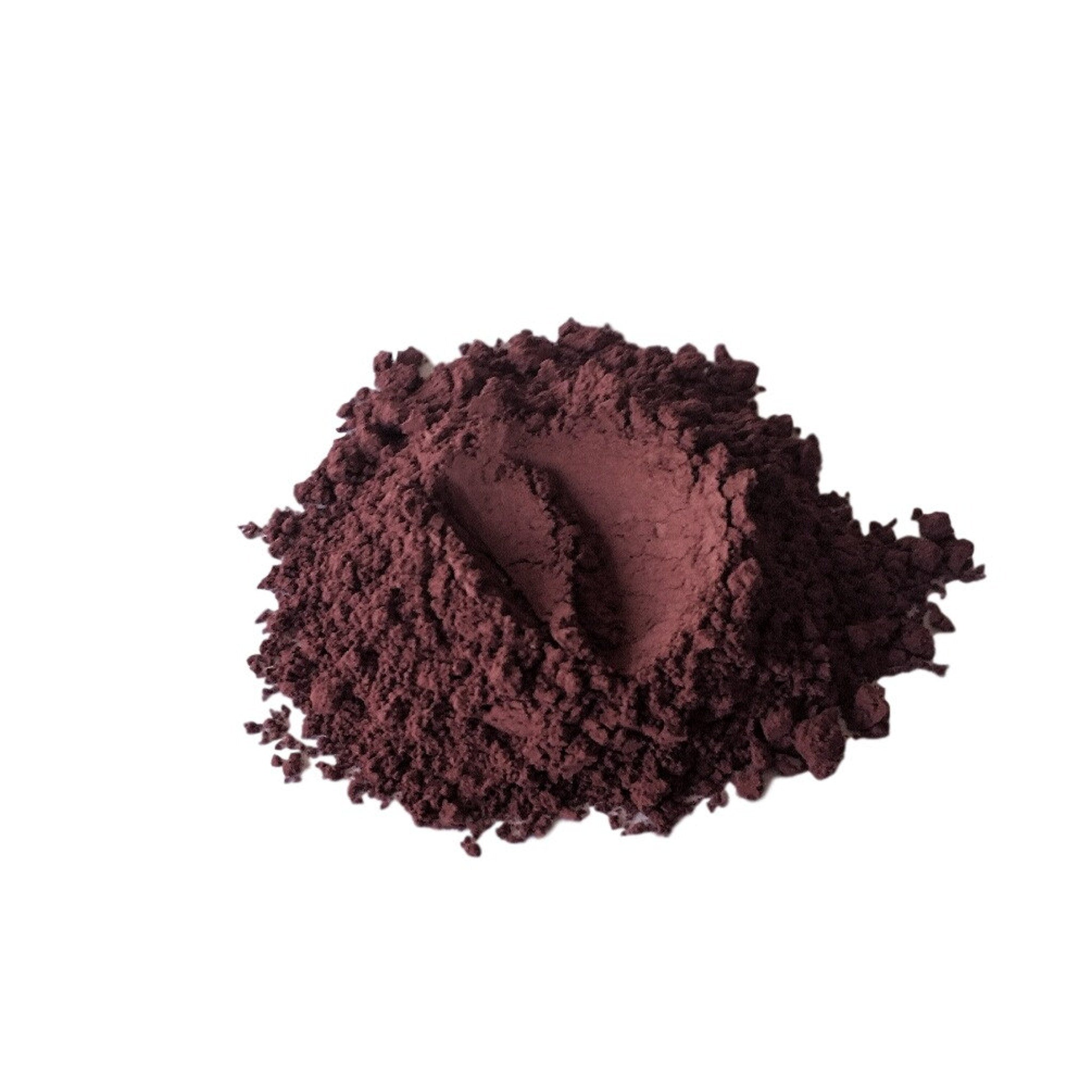 Powdered pigment in dark red color with a textured appearance on white background