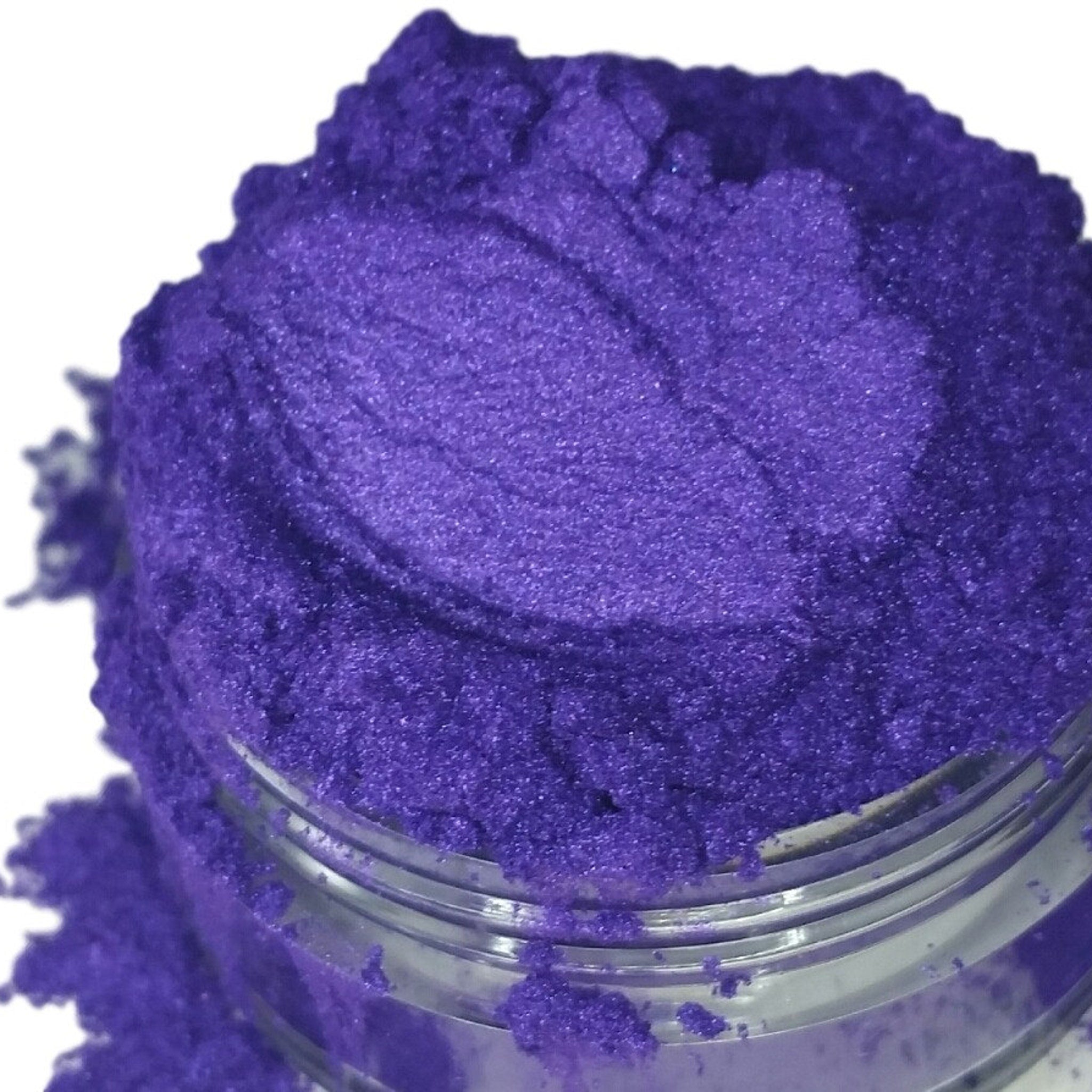Purple powder with metallic sheen in a clear jar, close-up view