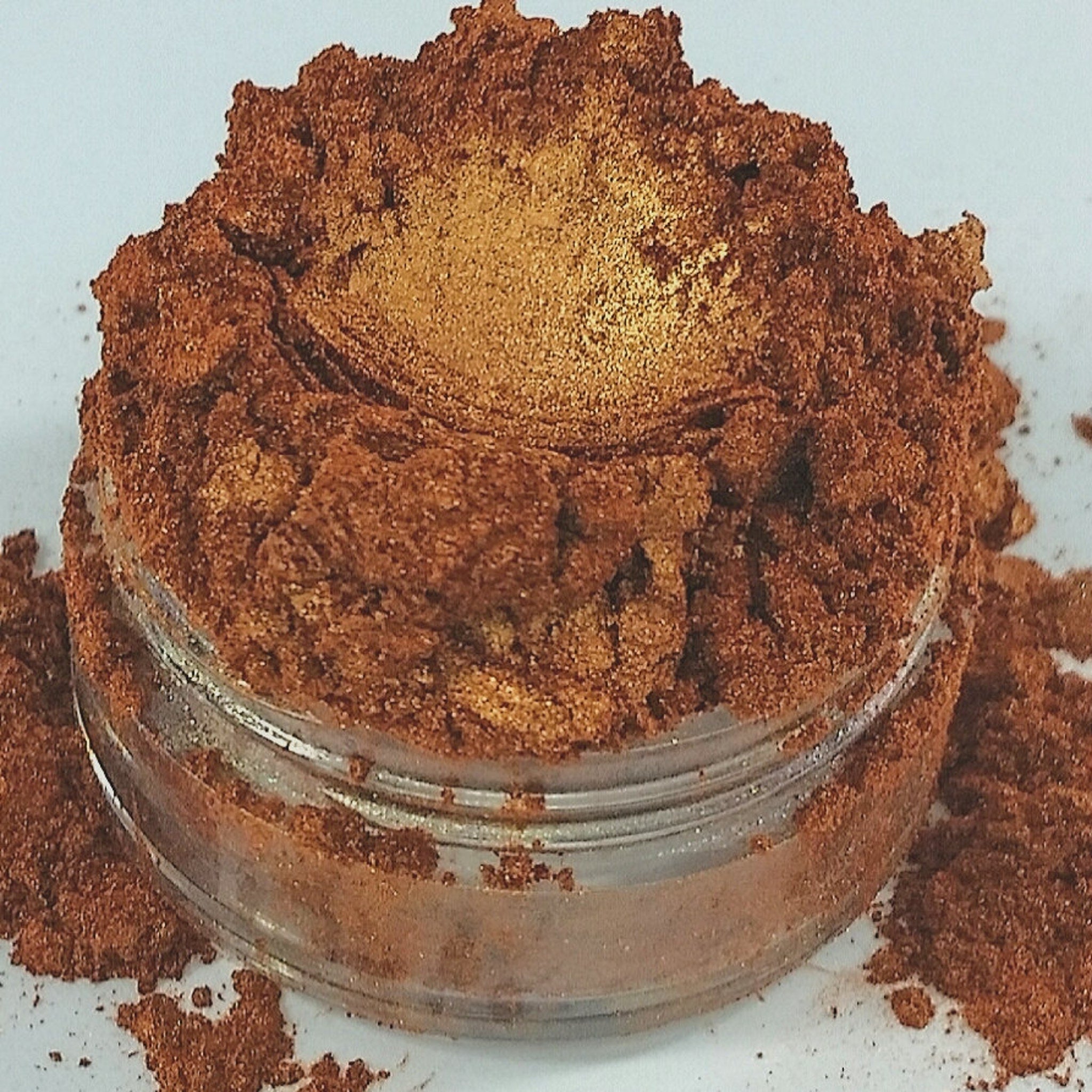 Hand applying shimmery purple-blue mineral eyeshadow with fingertip for a bold makeup look