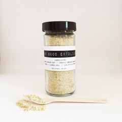 Facial cleanser in glass jar with black lid, Damn Good Exfoliant label, and wooden spoon