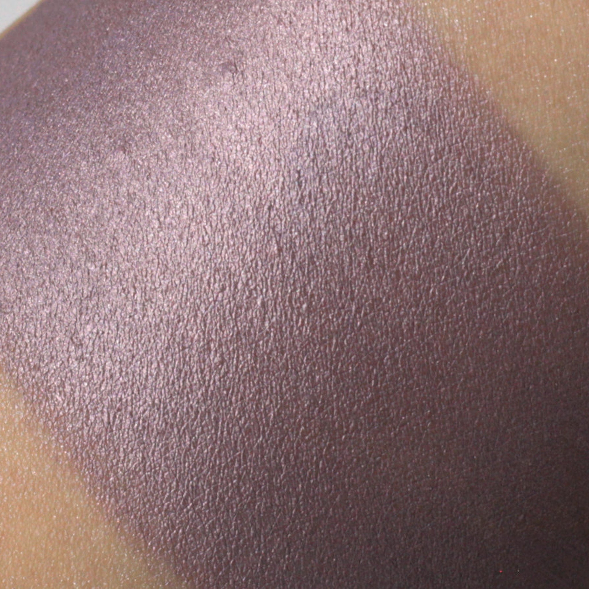 Close-up of vegan purple shimmer eyeshadow pan showing metallic sheen and smooth pressed powder texture