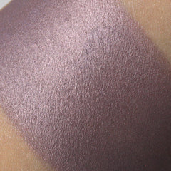 Close-up of vegan purple shimmer eyeshadow pan showing metallic sheen and smooth pressed powder texture