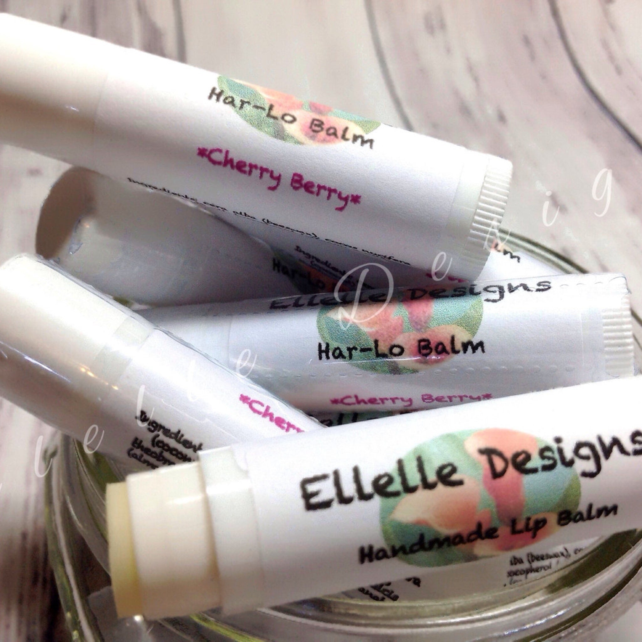 Lip balm tubes with white paper labels, "Ellelle Designs" and "Har-Lo Balm" text, for lip care