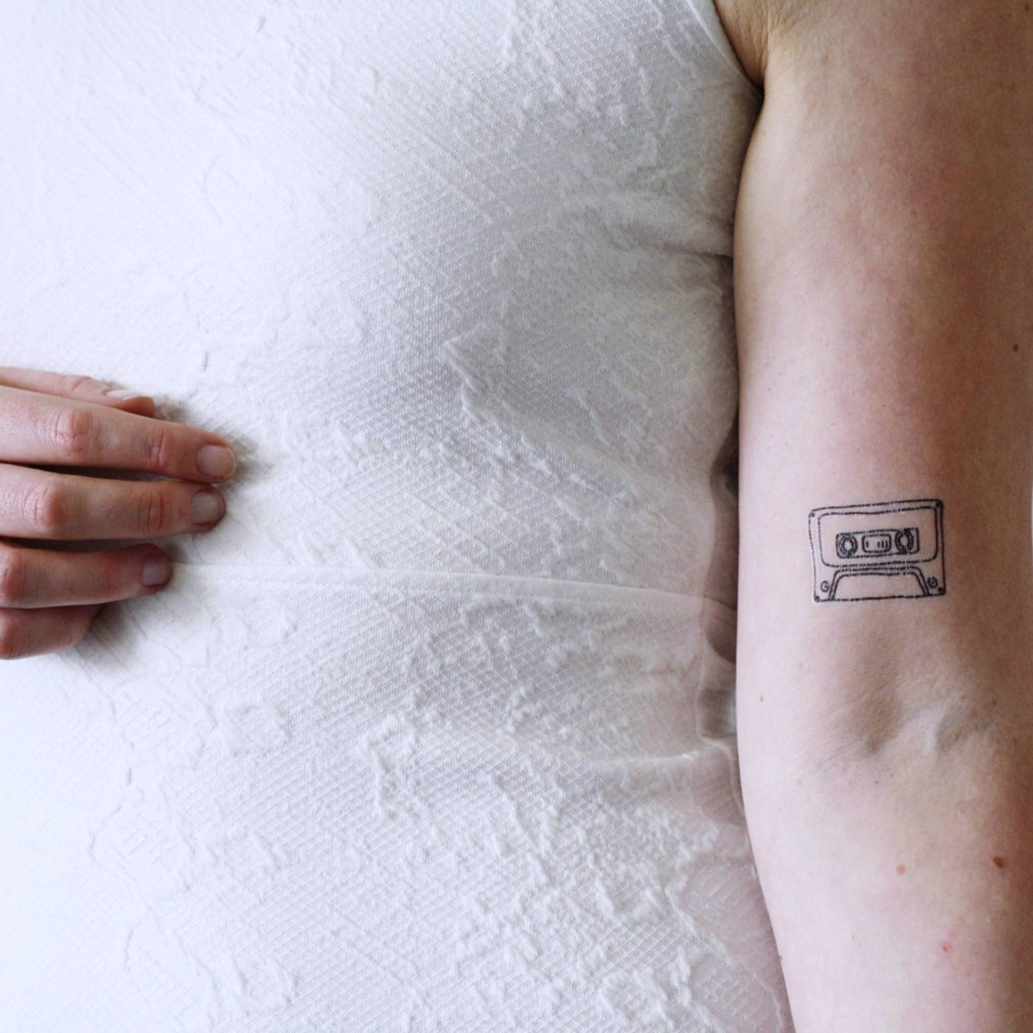 Cassette tape-shaped temporary tattoo sheet with 90s music designs on pink skincare-safe packaging