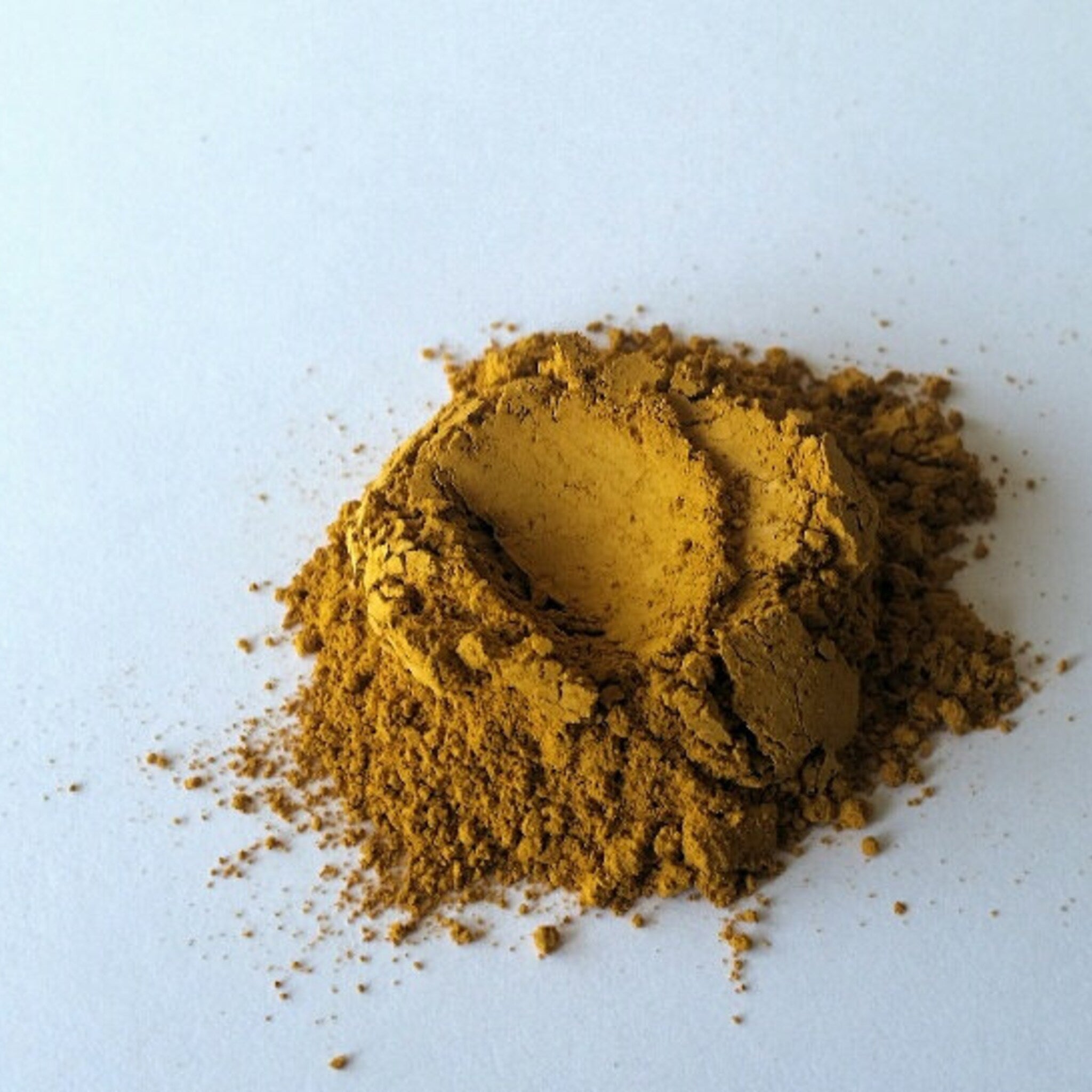 Yellow powder with a textured appearance on a white surface