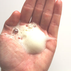 Foam bubbles on skin, white and yellow, in hand, for washing