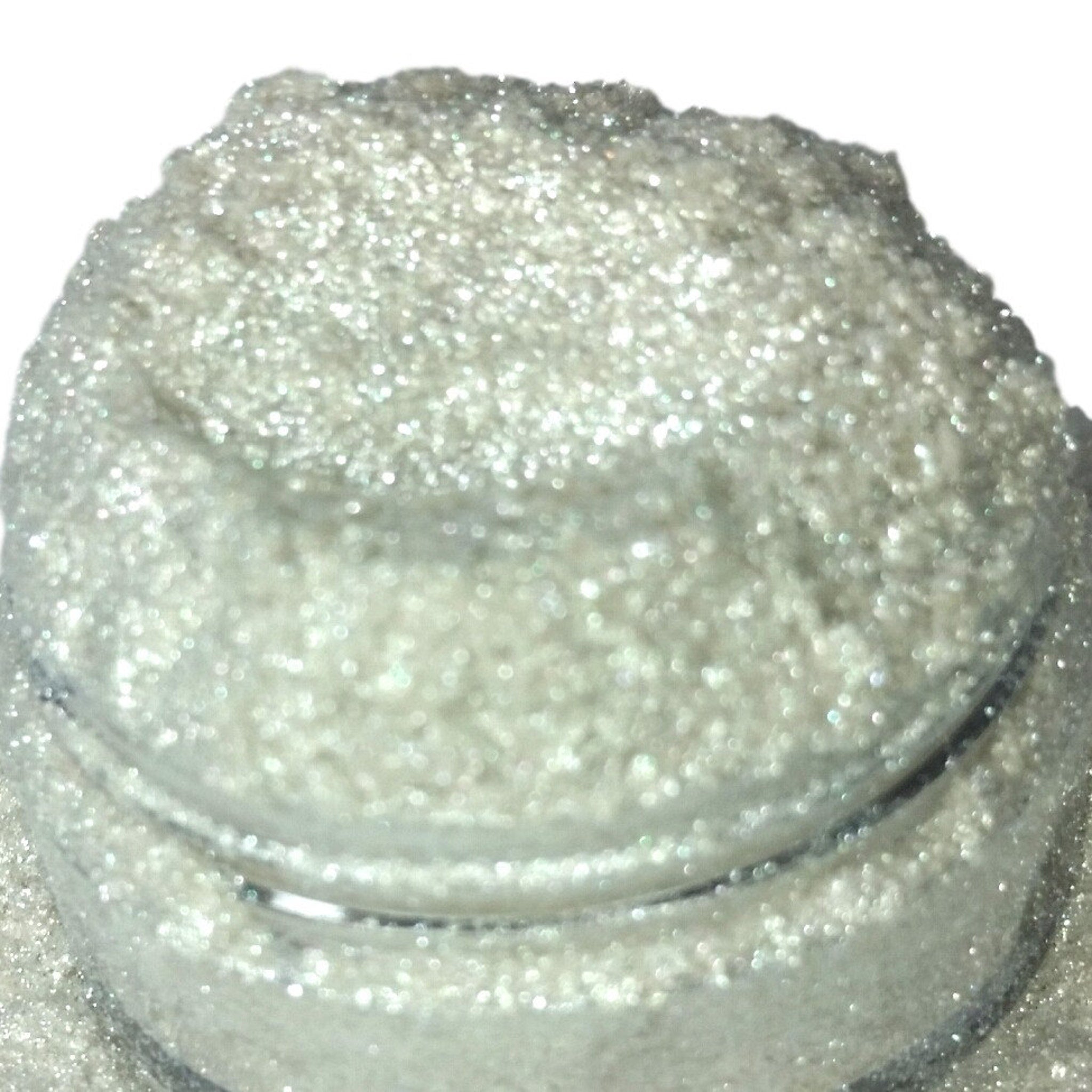 Shimmery white iridescent eyeshadow in compact with silvery glitter particles and sleek black case