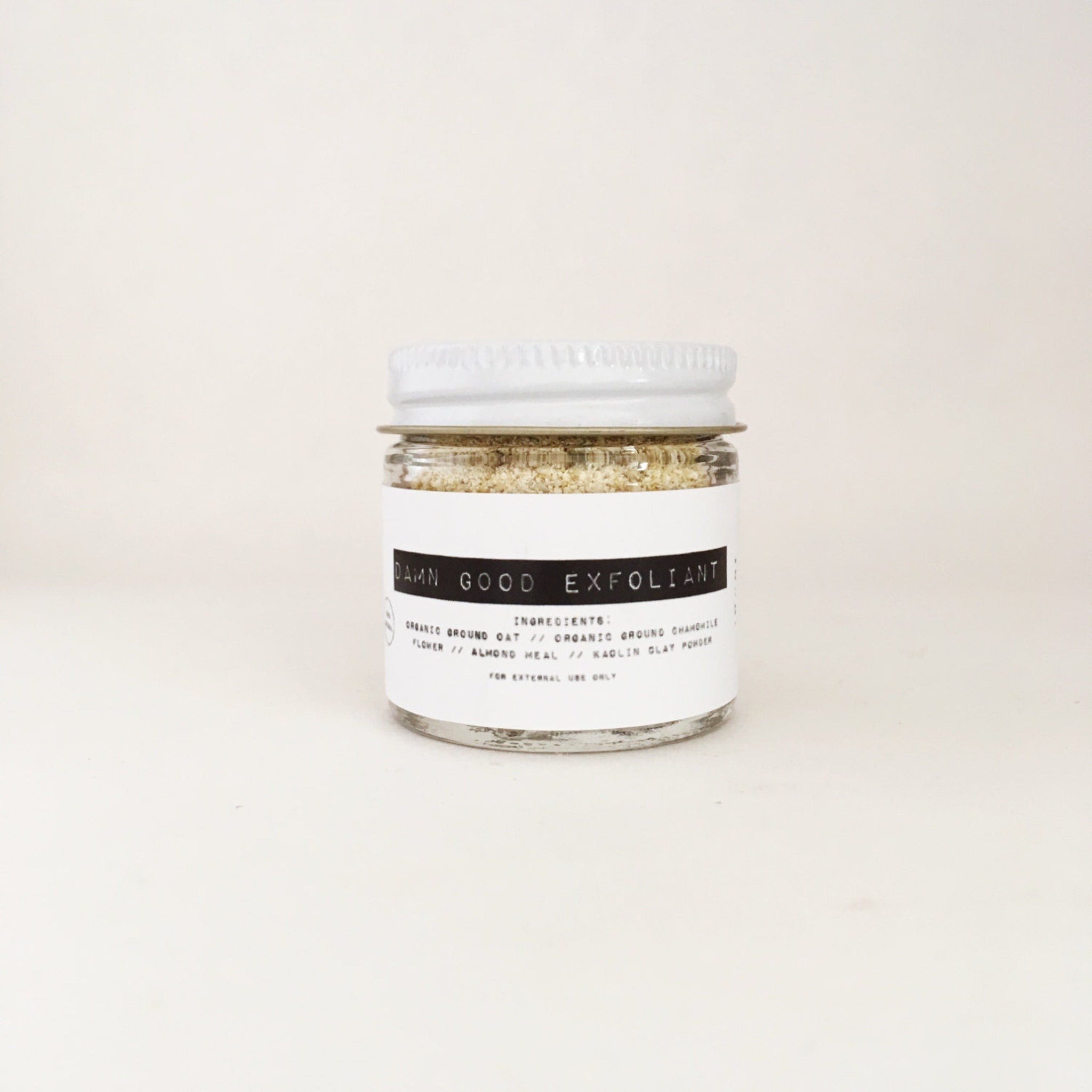 Exfoliant jar with white lid, clear glass, and white label with "Damn Good Exfoliant" text