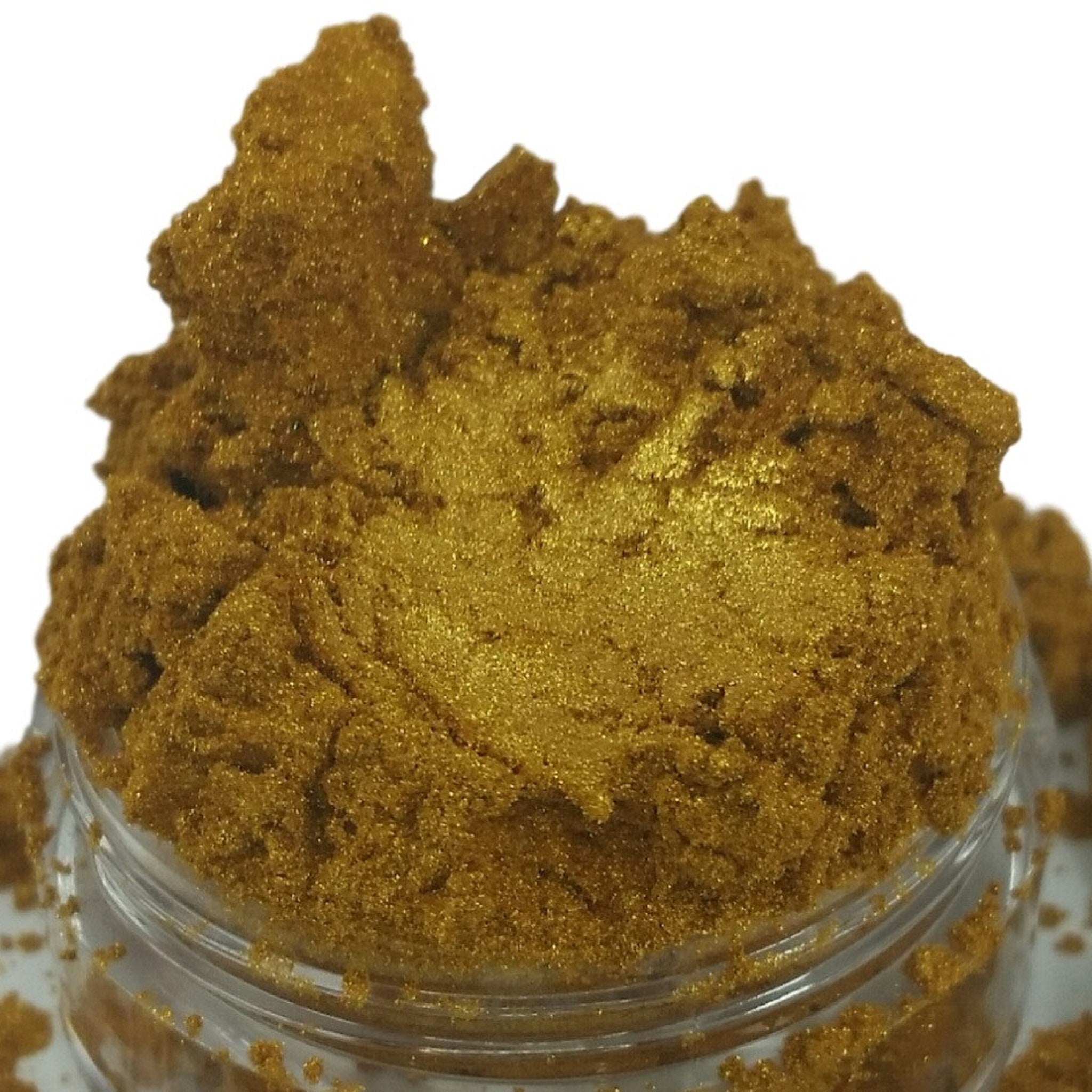 Gold powder with glitter, in a clear jar, with a granular texture.