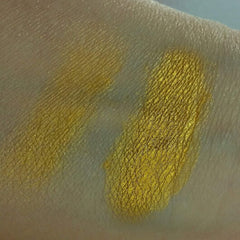 Close-up of fingertips applying iridescent blue-gold eyeshadow with metallic shimmer to eyelid