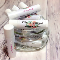 Lip balm tubes, white with pink text, in a glass jar, Ellelle Designs brand name visible