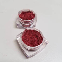 Close-up of burgundy shimmer eye shadow powder in sifter jar, showcasing berry-kiss metallic flecks