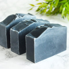 Charcoal soap bars, dark gray rectangular shape, textured surface, on marble countertop