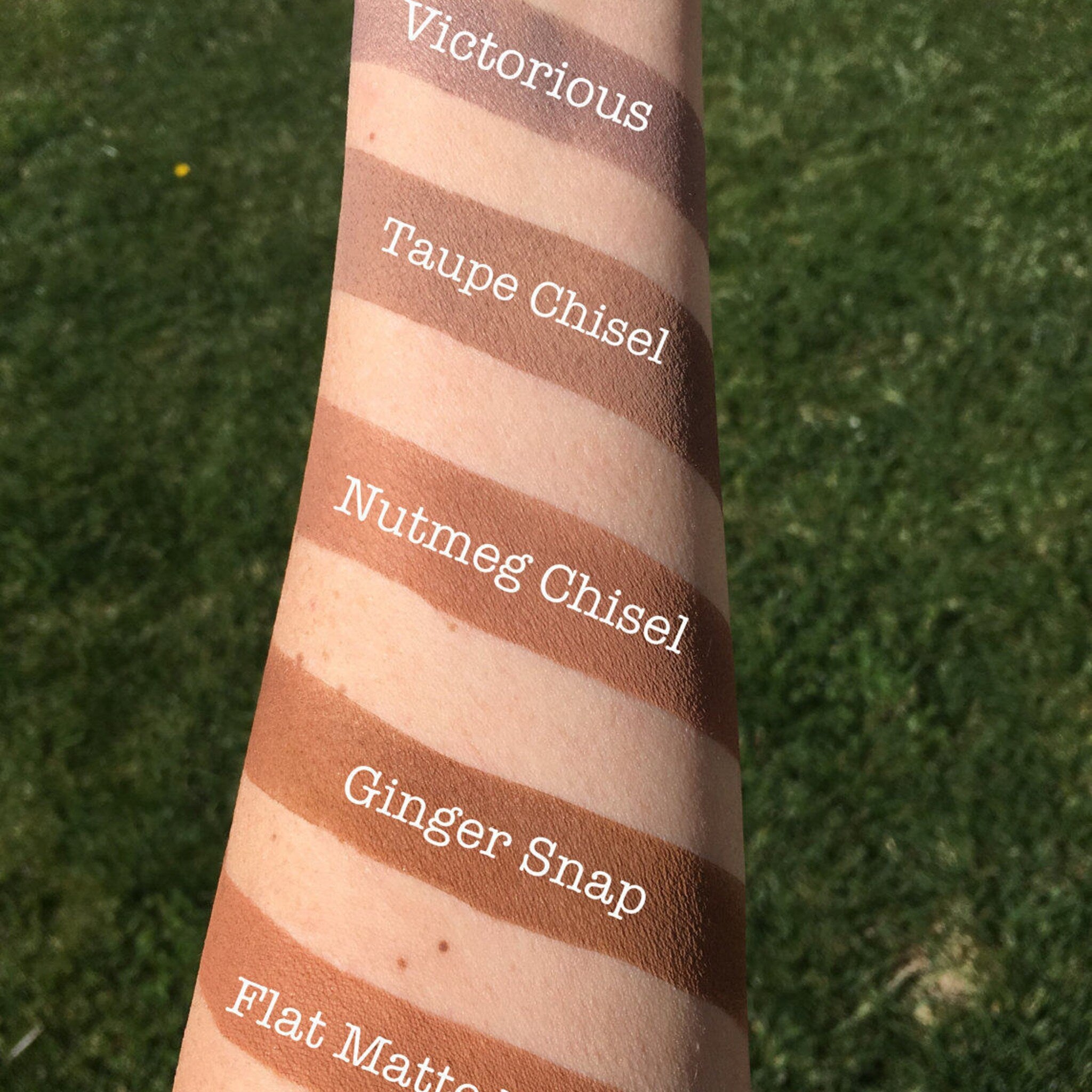 Makeup swatches in various brown shades on arm, with text labels in white font
