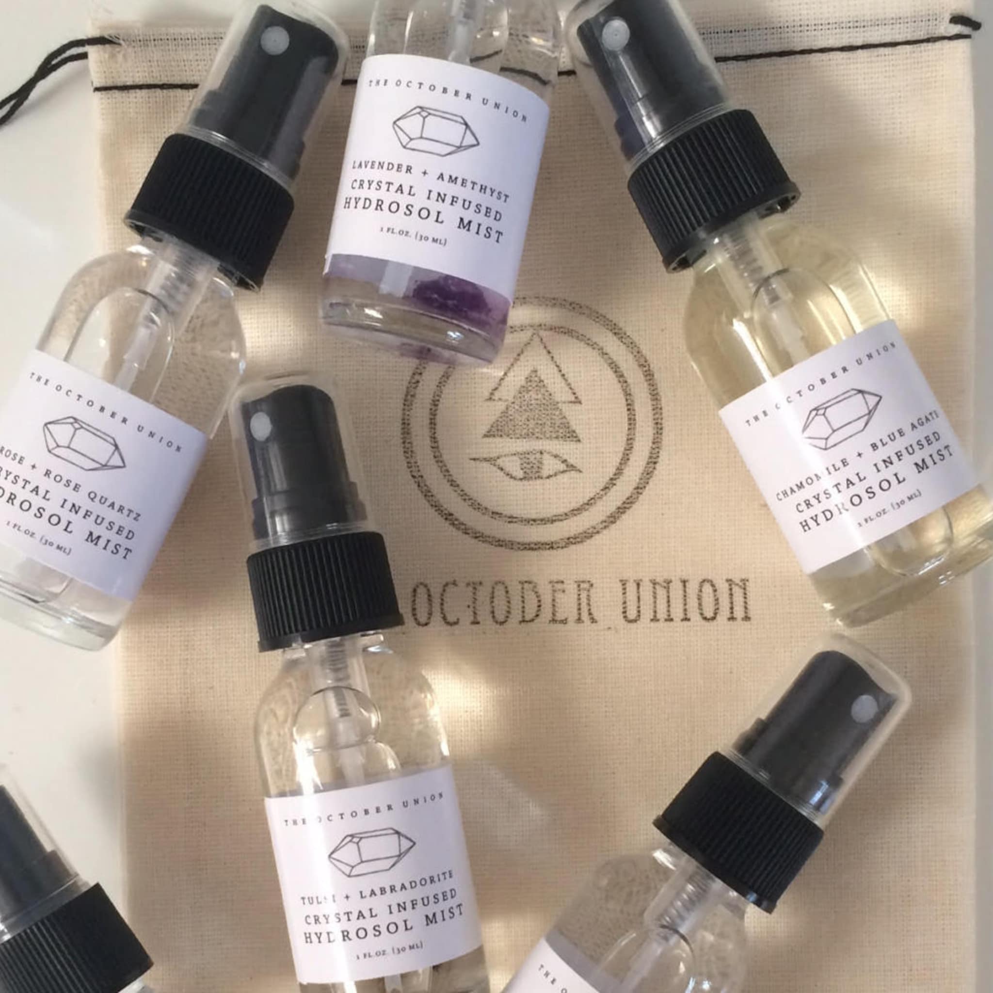 Hydrosol mist bottles with black spray tops, clear glass, and white labels with The October Union branding.