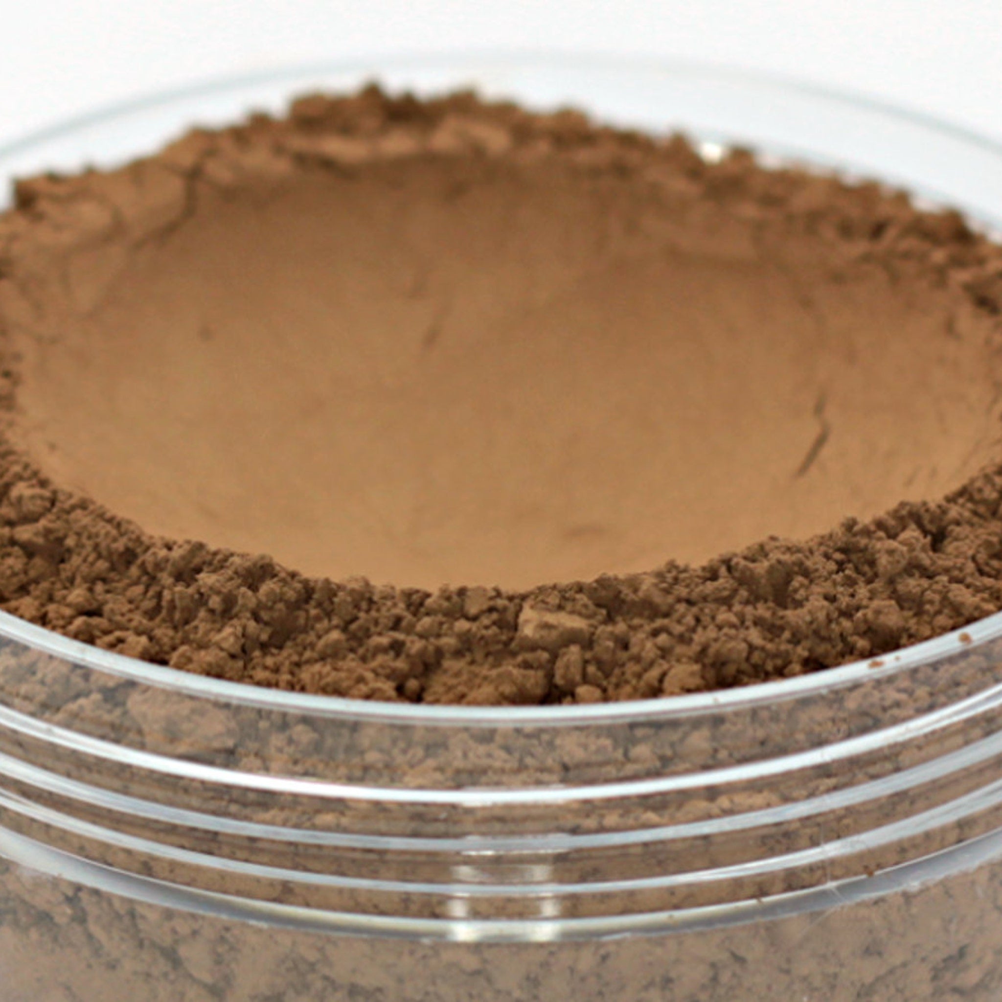 Vegan mineral powder foundation, dark brown powder, clear jar, layered texture