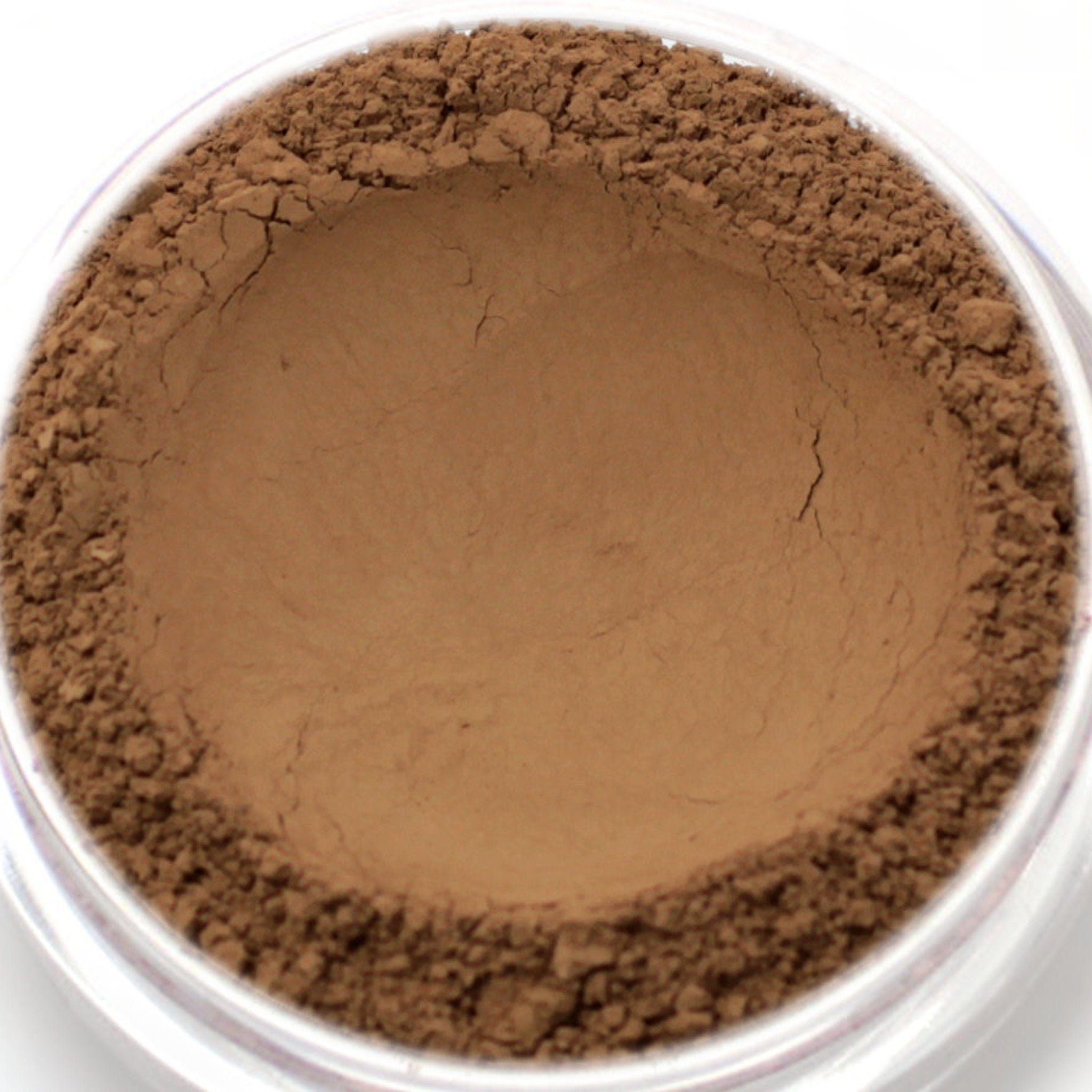 Powder makeup with brown color and granular texture in a clear container