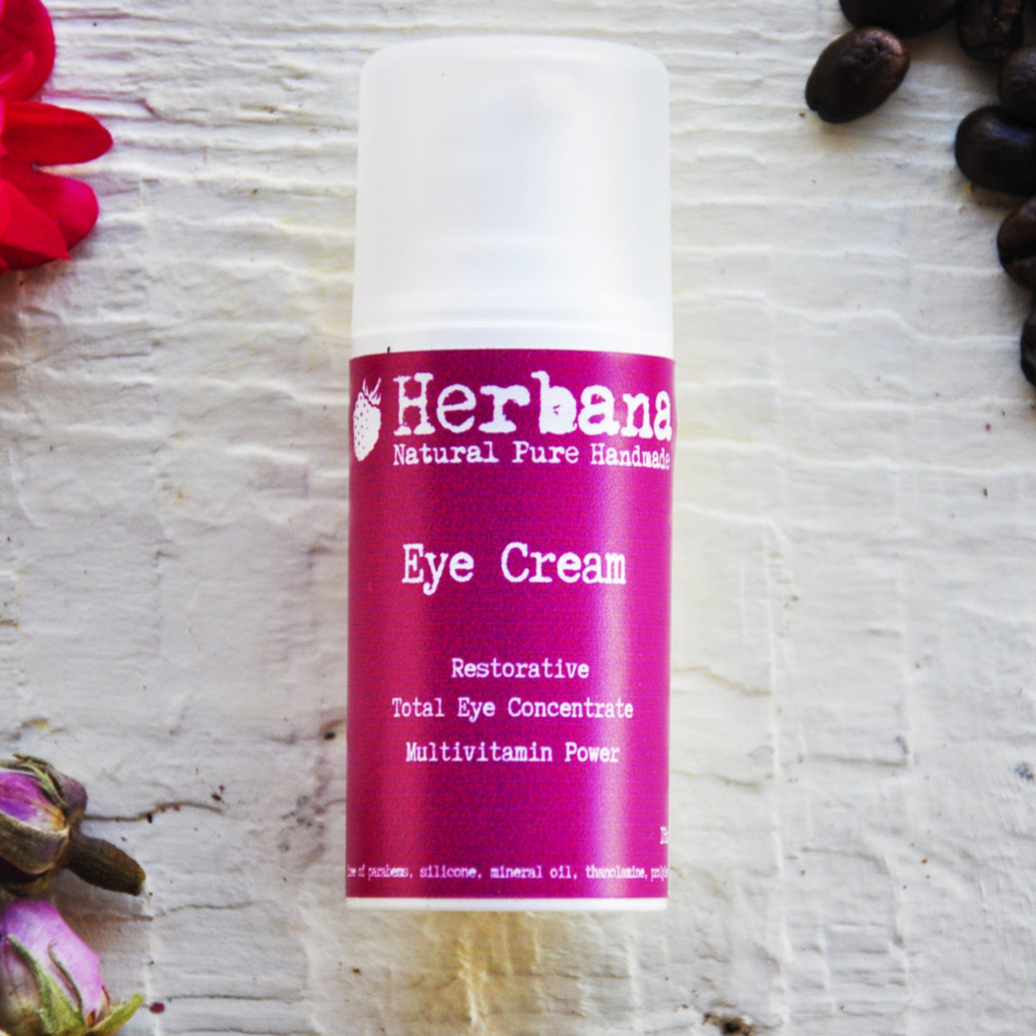 Eye Cream bottle with white cap and pink label, Herbana brand name visible, on white textured surface.