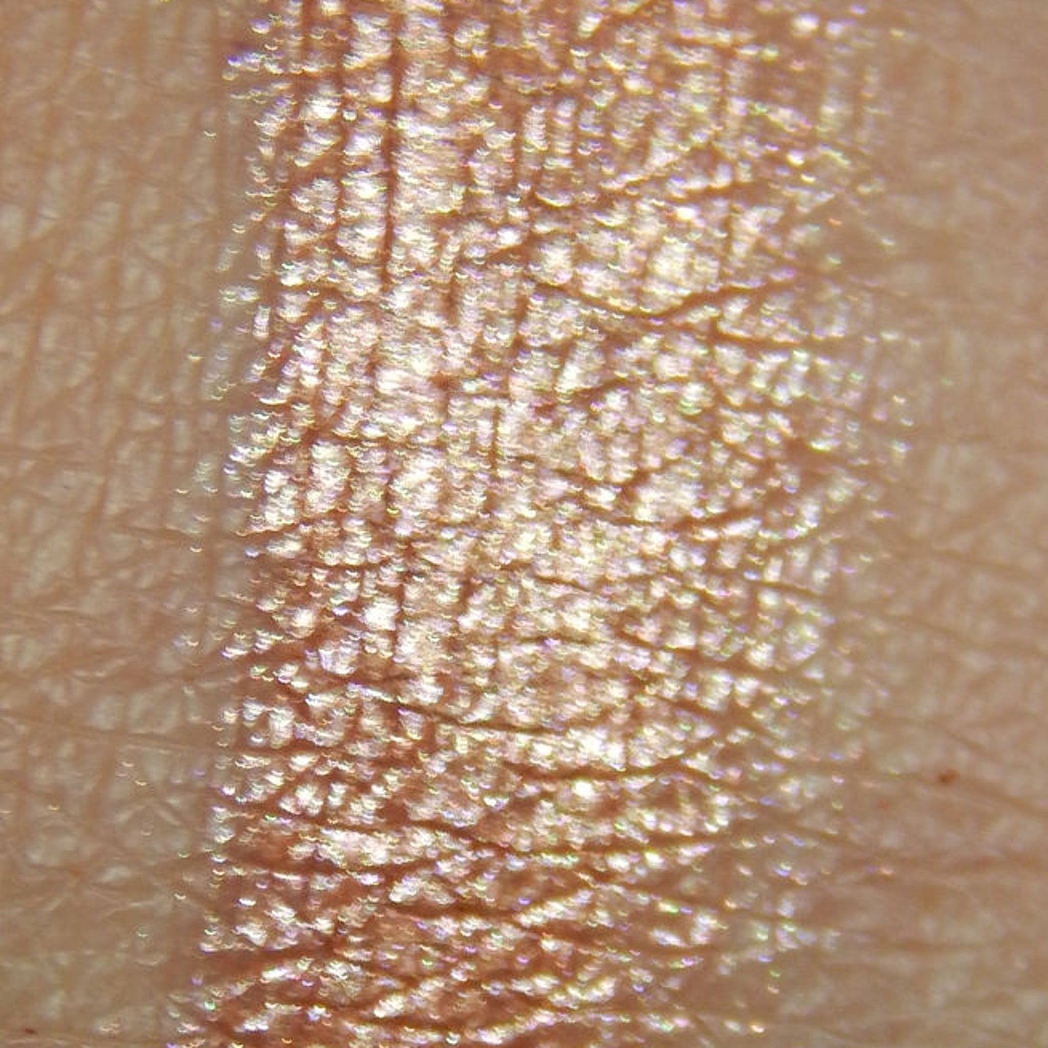 Close-up of peach-toned pressed powder eyeshadow with soft shimmer finish in compact case