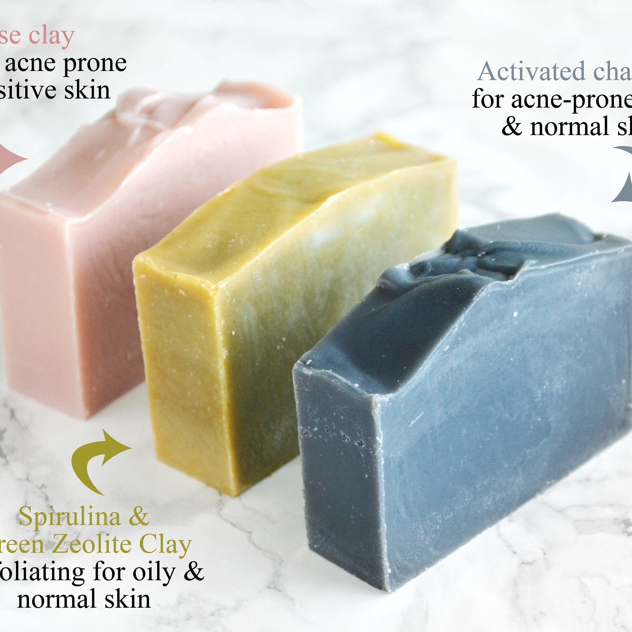 Soap bars in pink, green, and blue with visible texture on marble surface