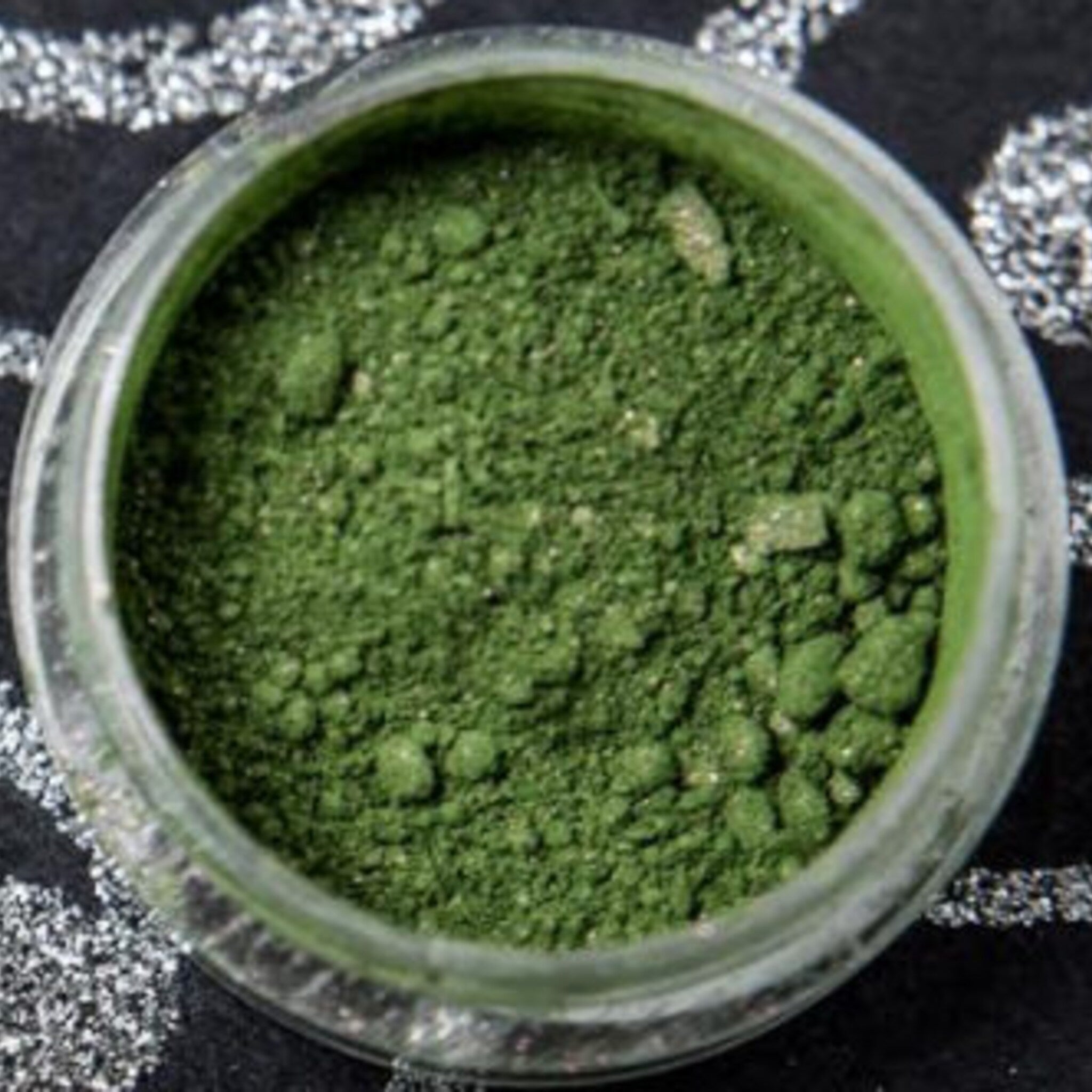 Close-up of vegan green eyeshadow with intense red duochrome shift and sparkling shimmer particles