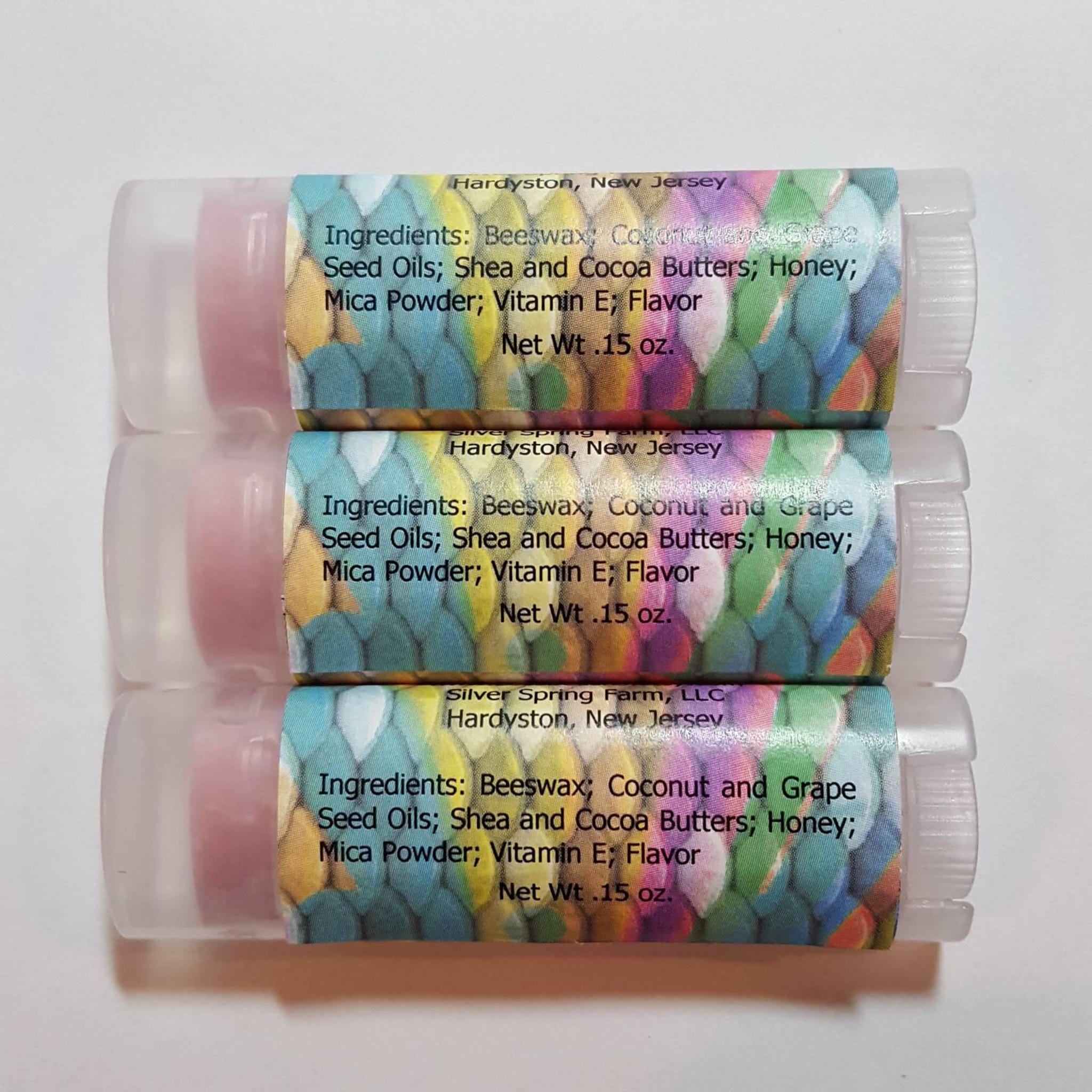Lip balm tubes with pink balm, clear plastic, and patterned labels with text
