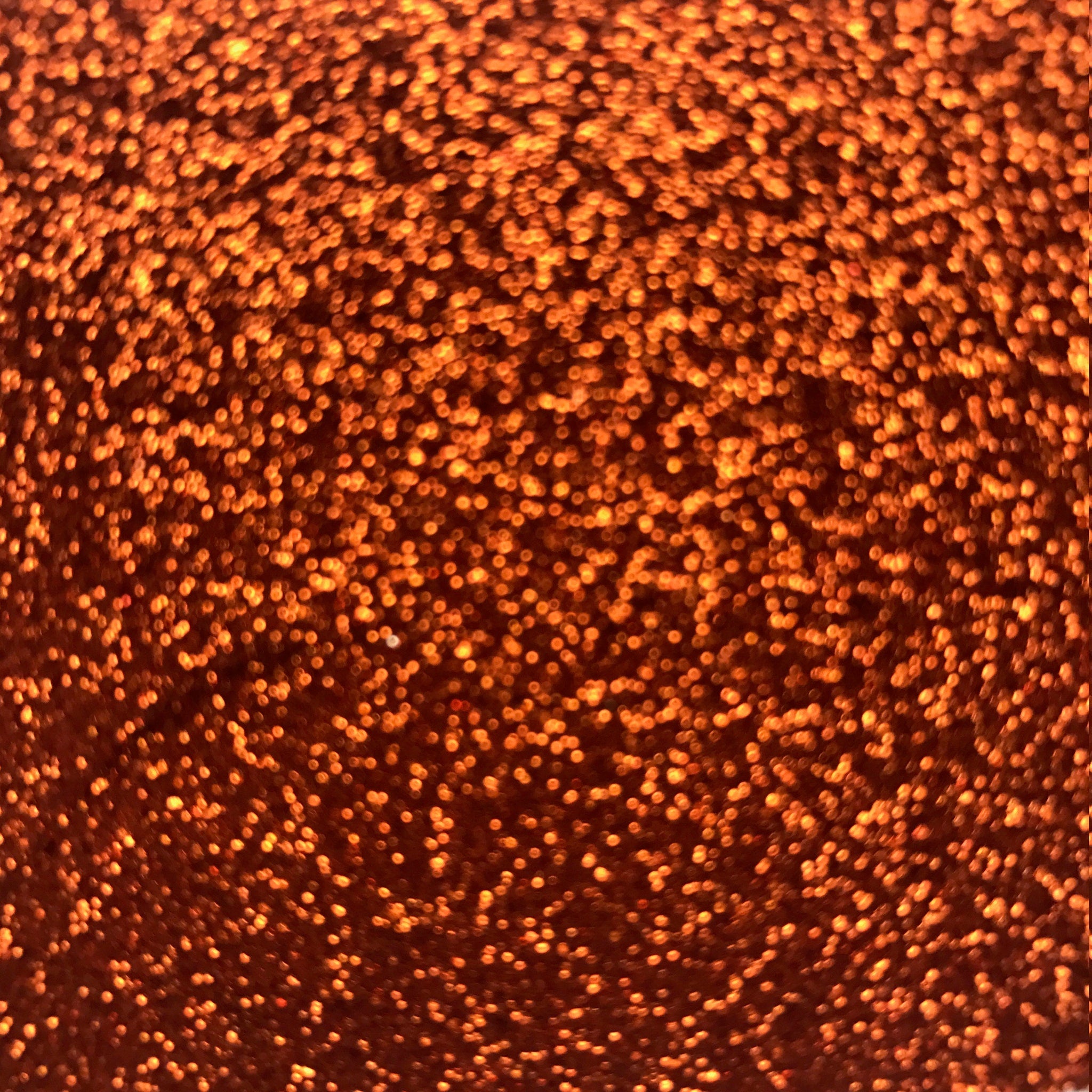 Side view of copper loose glitter eyeshadow in a small sifter jar, showcasing shimmer particles and texture.