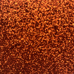 Side view of copper loose glitter eyeshadow in a small sifter jar, showcasing shimmer particles and texture.