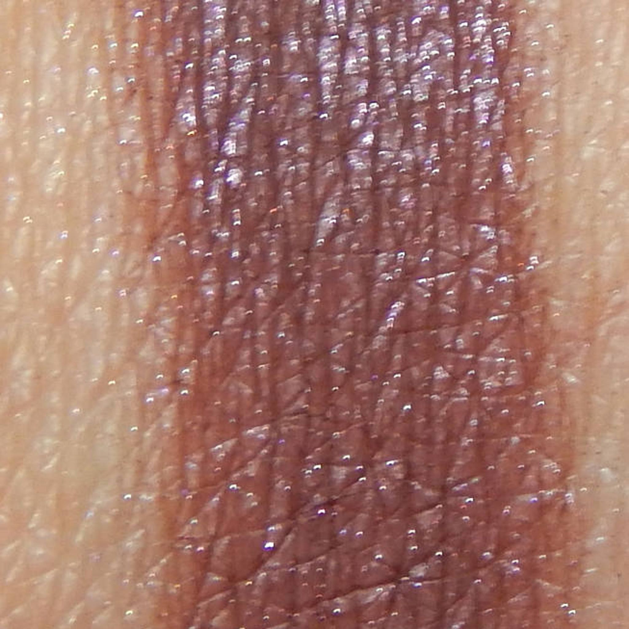 Close-up of Escapade Eye Shadow pan showing shimmering bronze pigment with smooth, blendable texture
