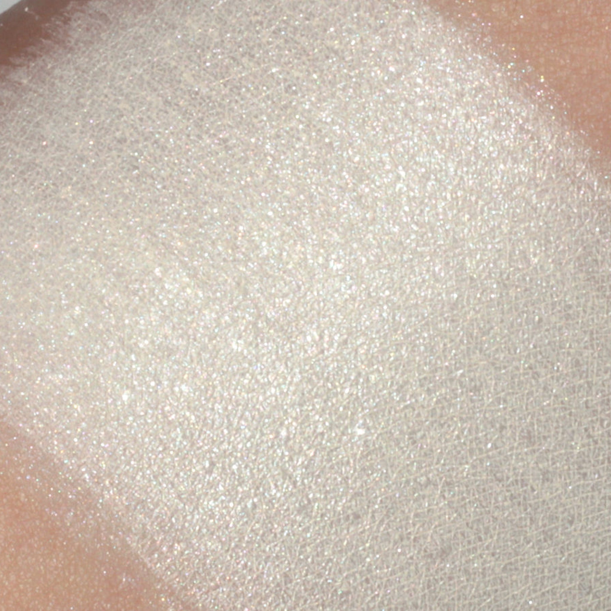 Close-up of creamy ivory white vegan eyeshadow with frost finish in compact case