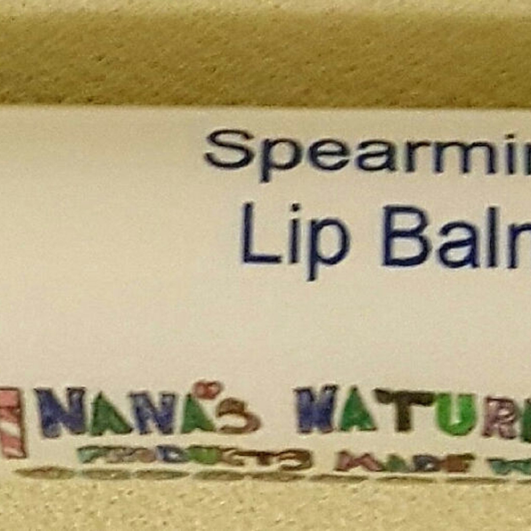 Lip balm product label with Spearmint text, Nana's Nature brand, and beige background.