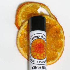 Lip balm with black cap, white label, and orange fruit slices on white background