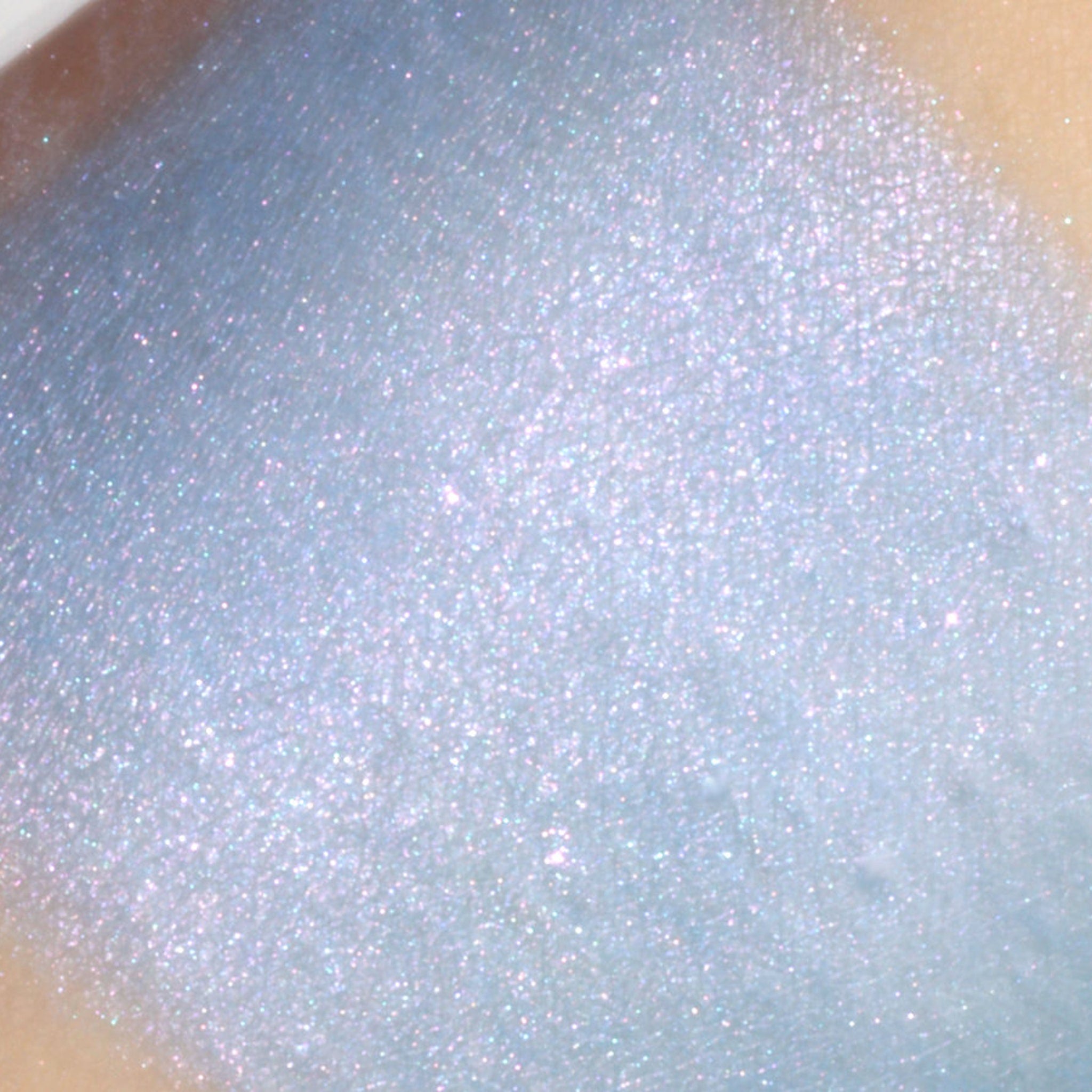Side angle view of Crystal Castle vegan mineral eyeshadow pot showing blue base with pink and turquoise shimmer particles.