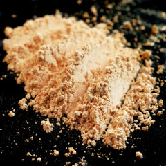 Side view of matte pastel peach loose pigment eyeshadow in a sifter jar with apricot ivory undertones