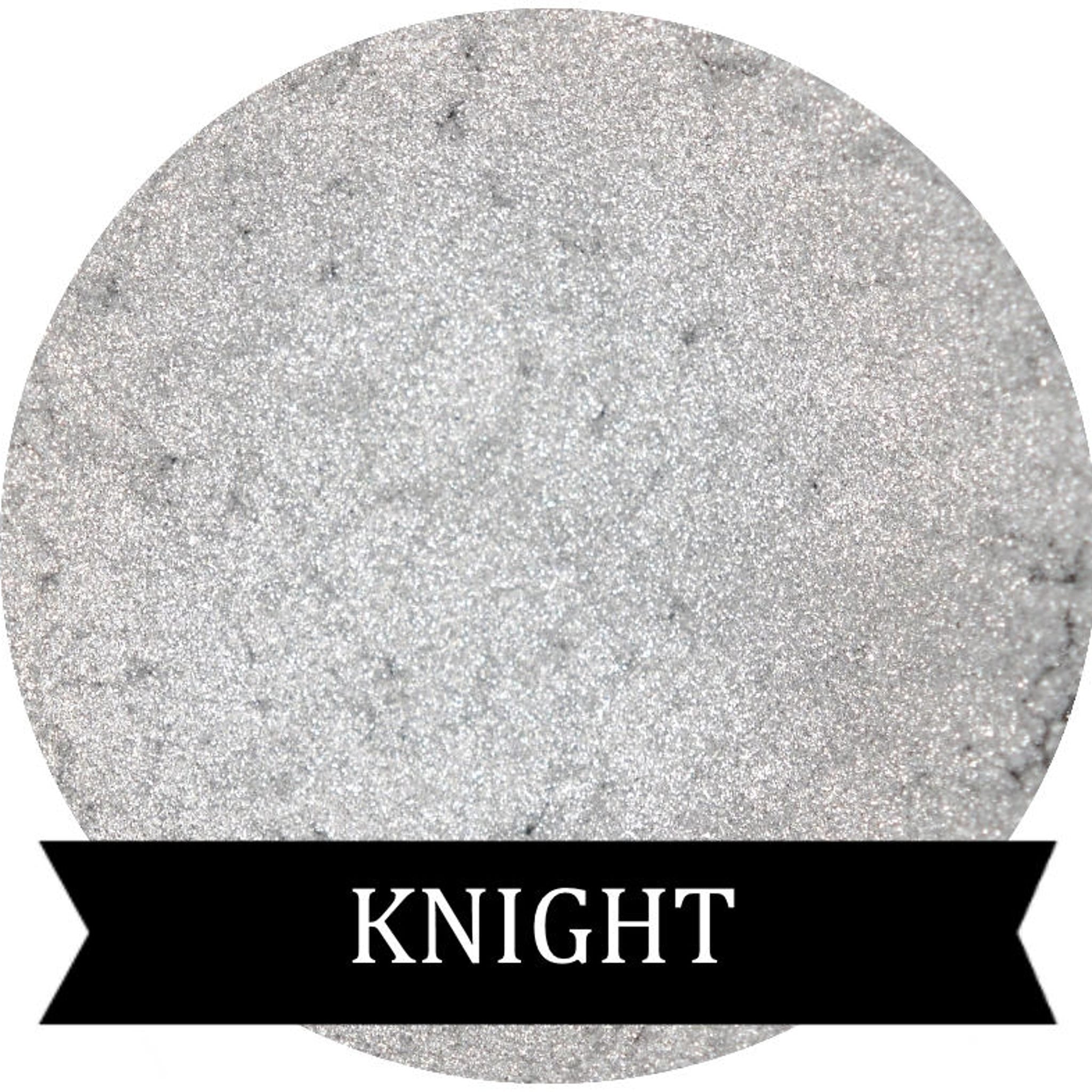 Metallic silver eyeshadow pot with reflective finish and sleek black compact packaging