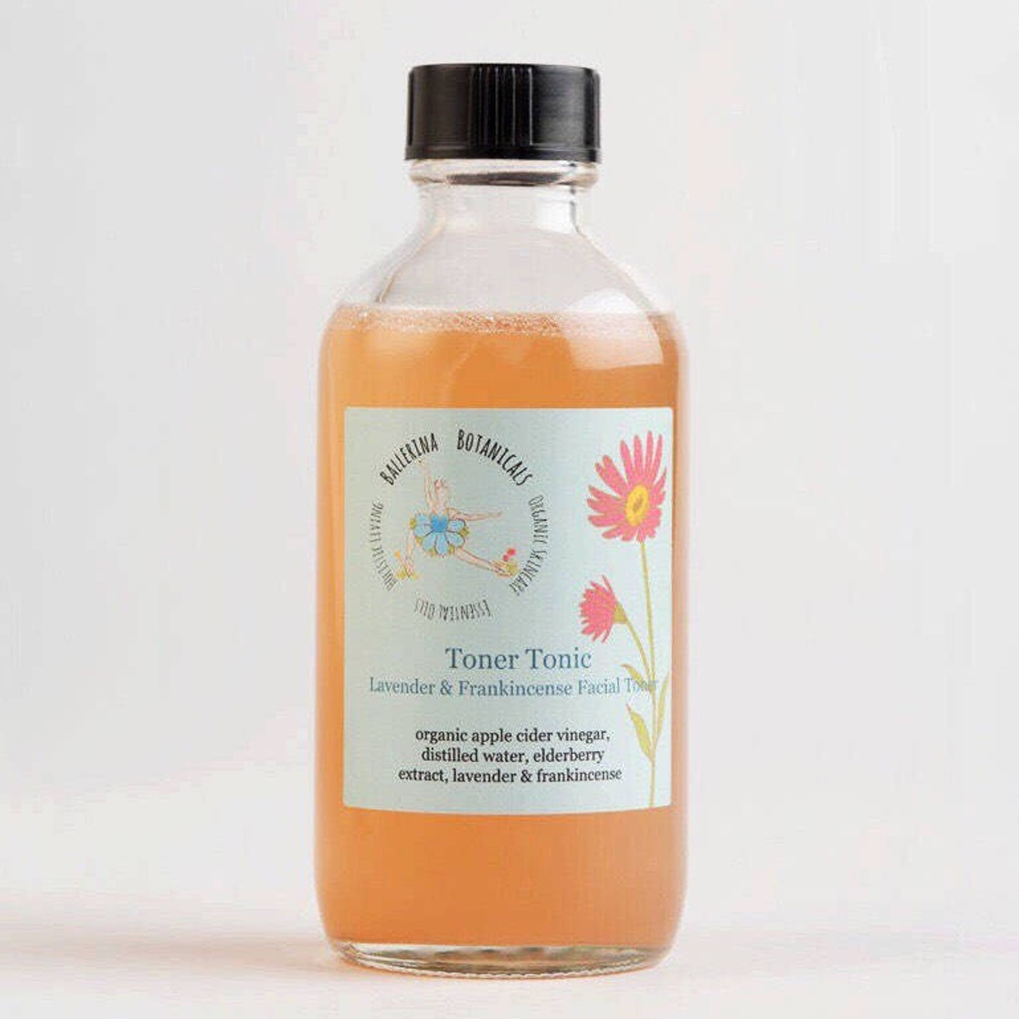 Toner Tonic bottle with orange liquid, black cap, and label with floral design
