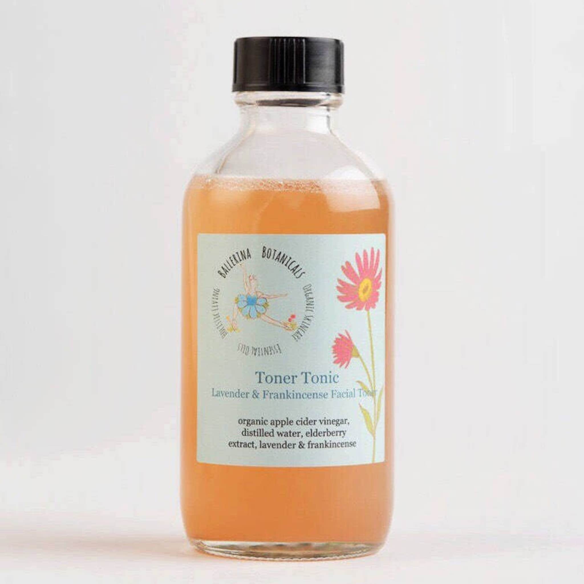 Toner Tonic bottle with orange liquid, clear glass, and black cap, Ballerina Botanicals label visible