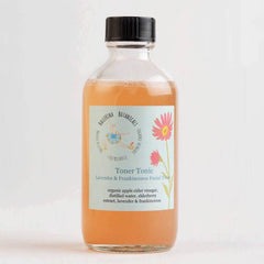Toner Tonic bottle with orange liquid, clear glass, and black cap, Ballerina Botanicals label visible