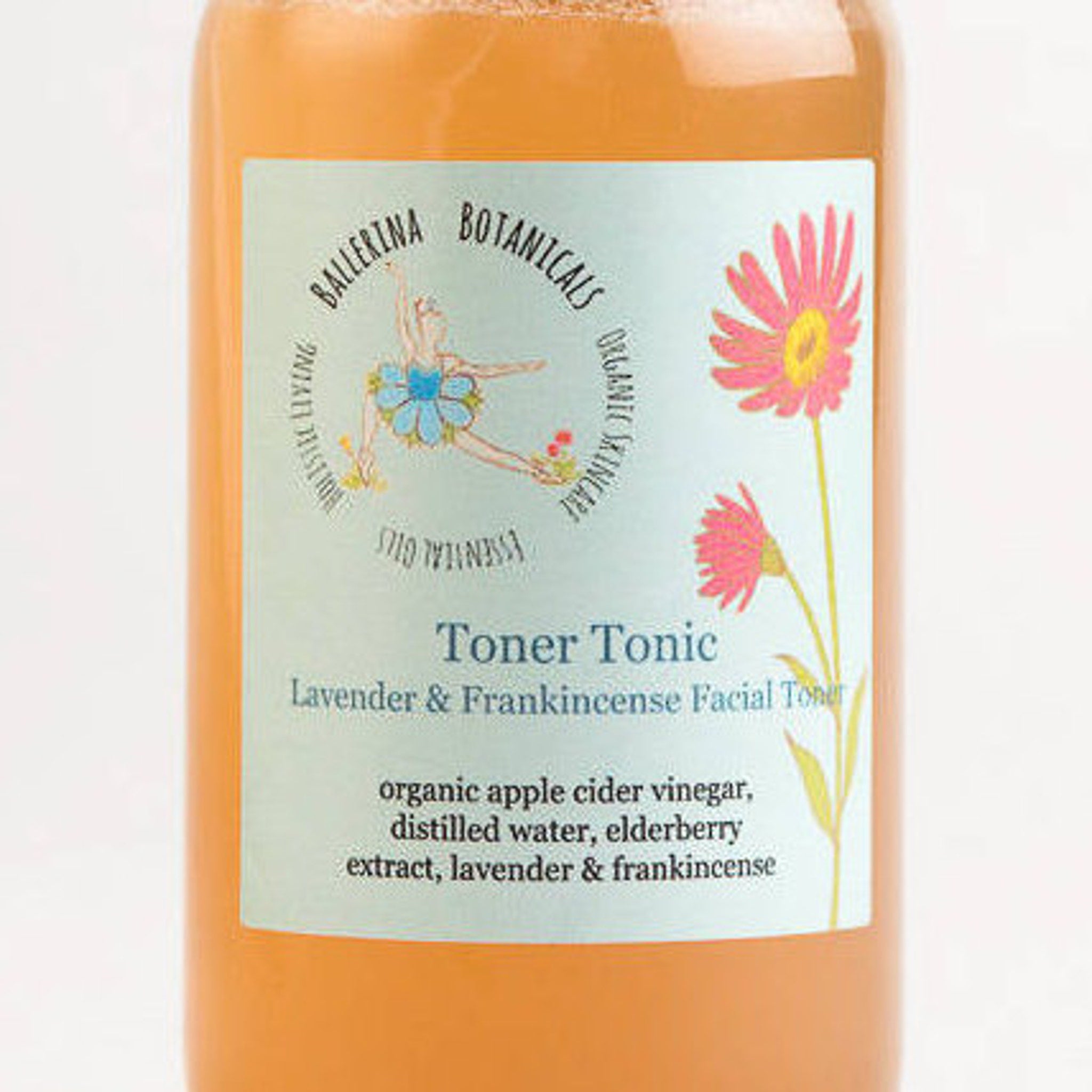 Toner Tonic bottle with orange liquid, light blue label, and pink floral illustration