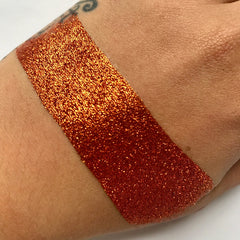 Close-up of sparkling copper loose glitter eyeshadow with fine shimmer particles catching the light