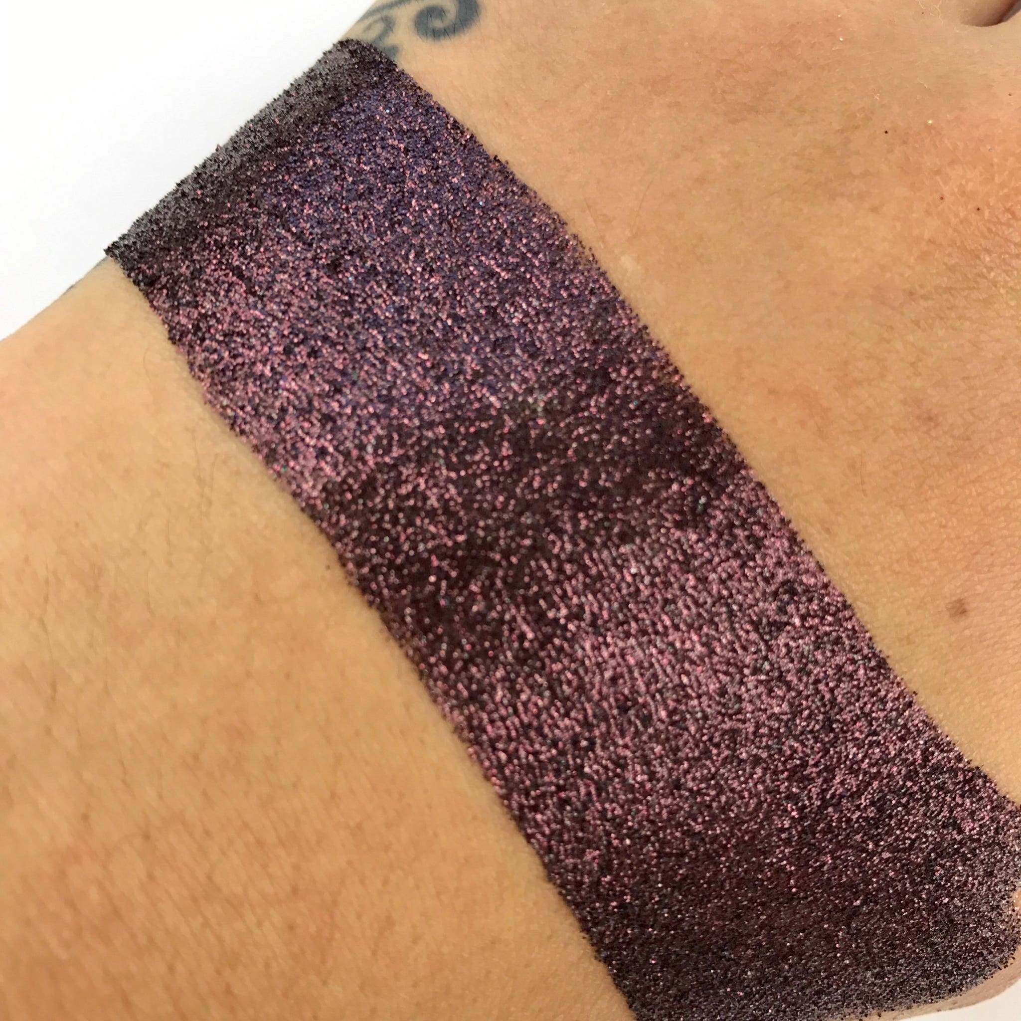 Close-up of mocha brown loose glitter eye shadow with shimmering particles in a glass jar
