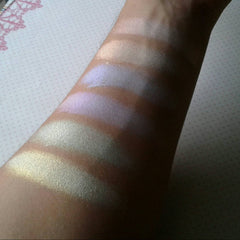 Highlighter swatches with gold, purple, and silver shimmer on arm for color comparison