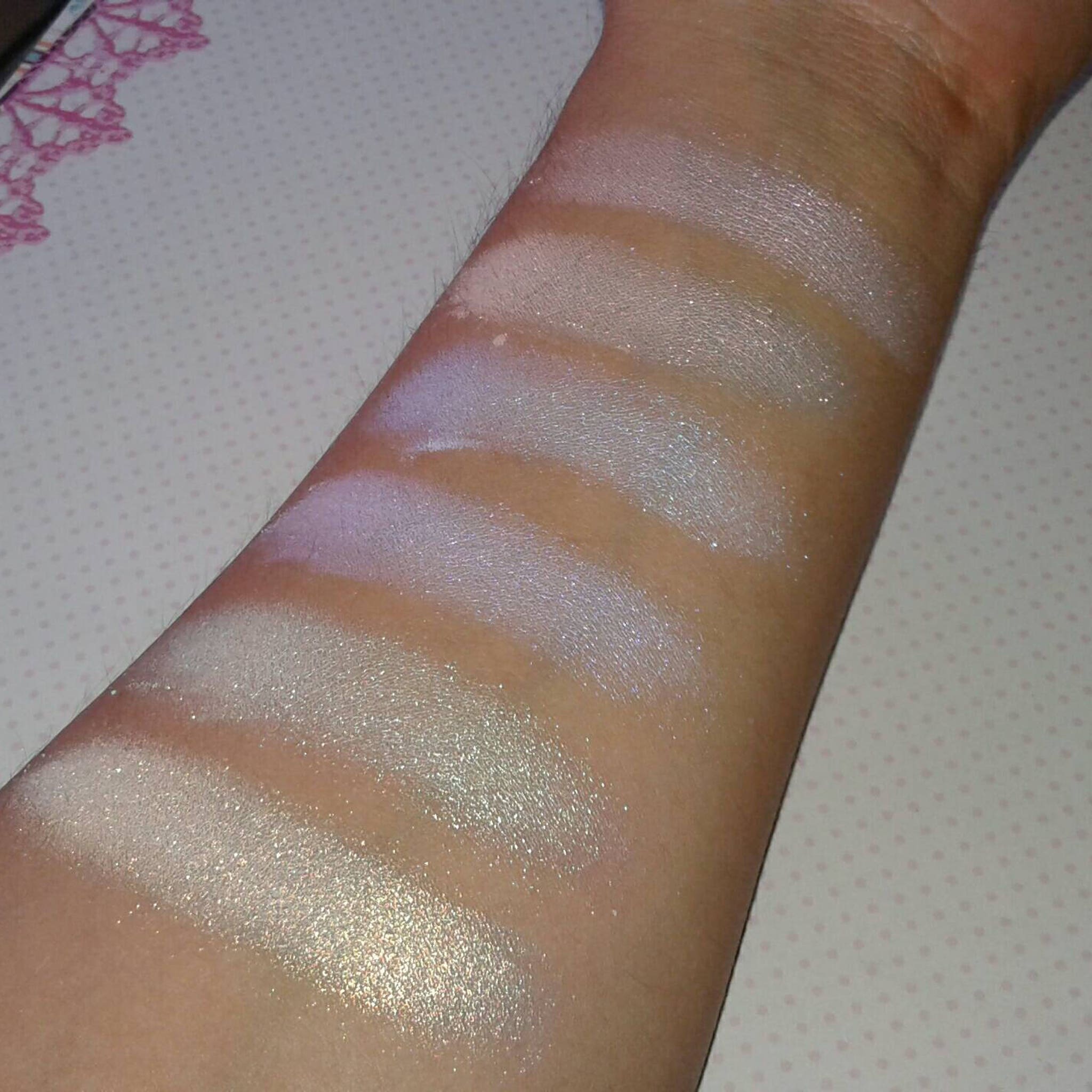 Swatch samples of shimmering white and iridescent makeup on arm, showing color and texture